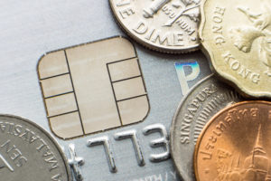 Microchip credit card and coins from different currencies close-up