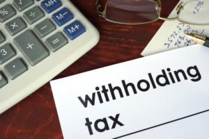Withholding tax written on a paper. Financial concept.